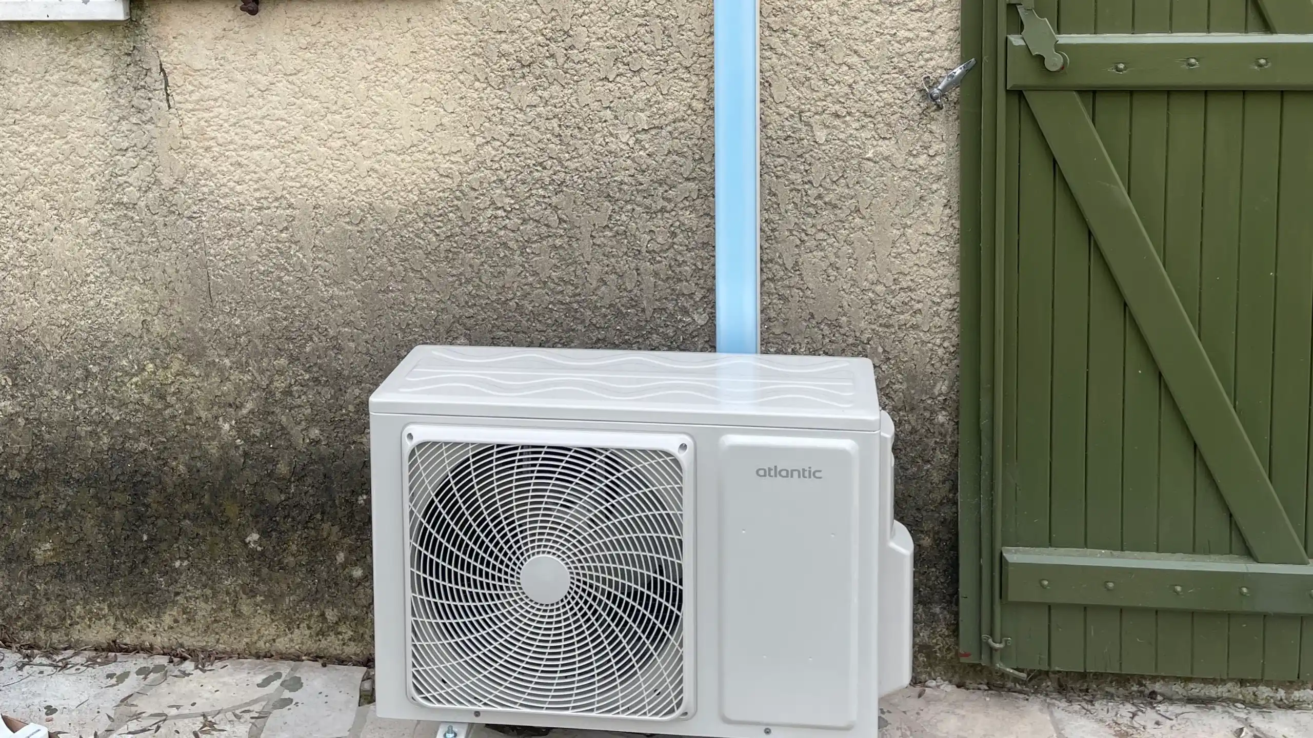 Climatisation installée contre une maison provençale aux volets verts près d'Avignon