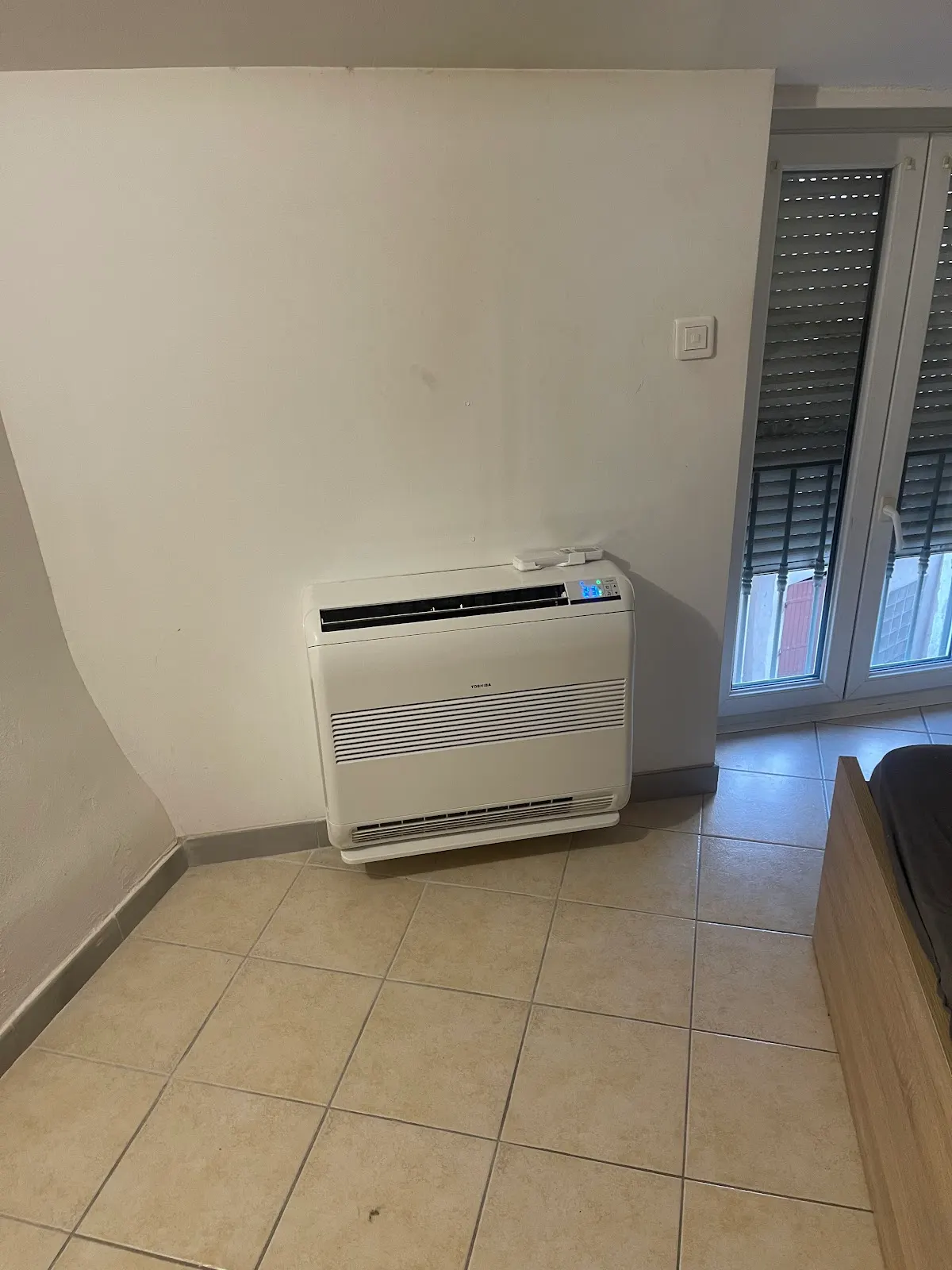 Climatiseur console posé au sol près d'une baie vitrée