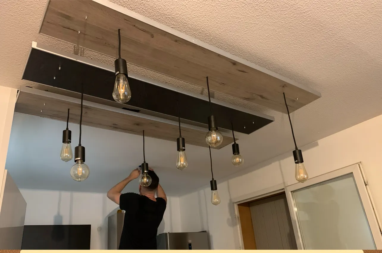 Lucas Le Bihan, électricien à Avignon, en train de poser un lustre sur mesure