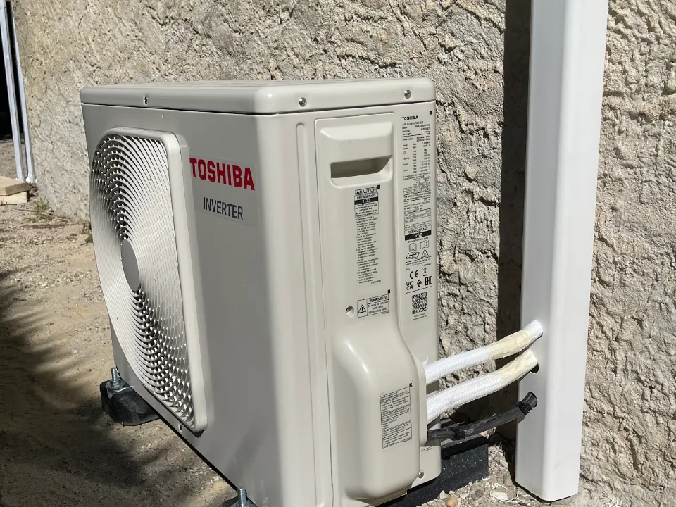 Unité extérieure de climatisation Toshiba posée sur un mur crépi