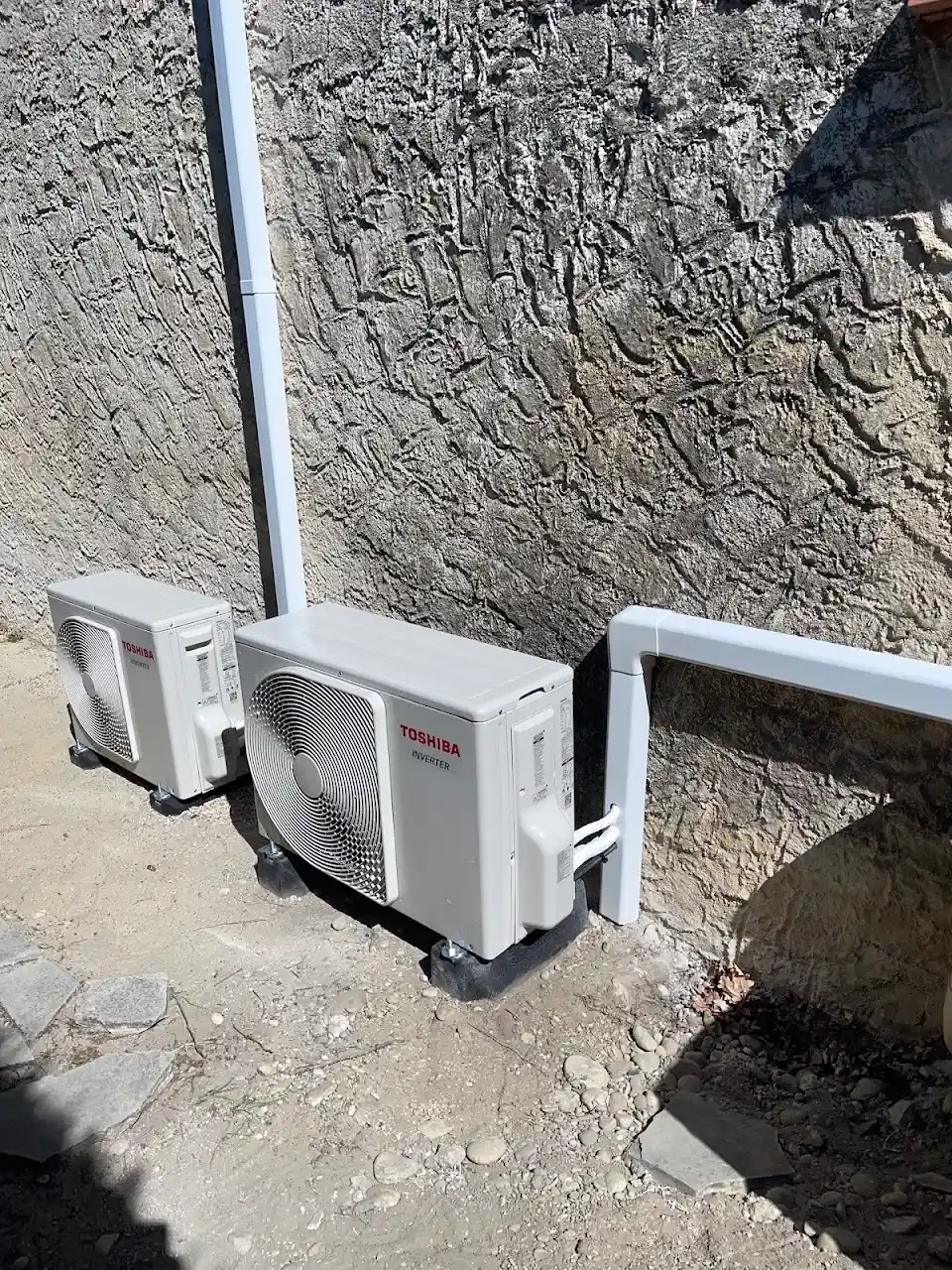 Deux groupes extérieurs de climatisation posés au sol contre une façade