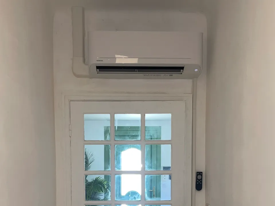 Climatiseur mural installé au-dessus d'une porte vitrée à Avignon