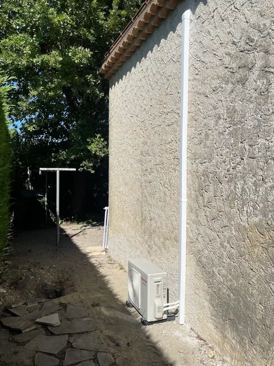 Unité extérieure de climatisation et goulotte le long d'un mur de jardin